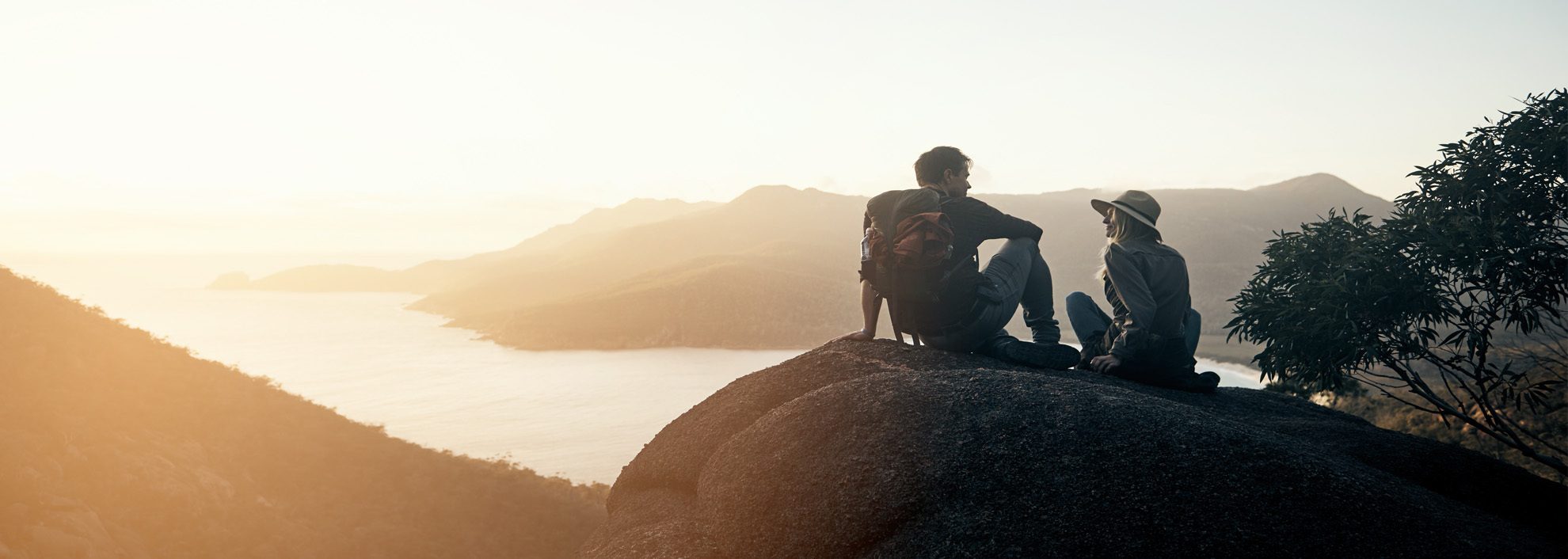 Young couple on mountain watching the sunrise